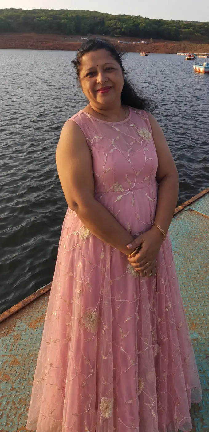 Founder of Ranisa Boutique wearing a pink embroidered dress beside a lake